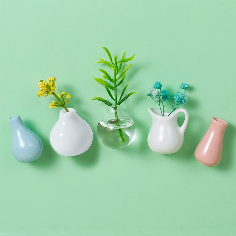 Set of small vases with plants on a light green background