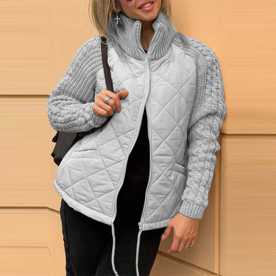 Woman wearing a gray quilted jacket with a beige wall background