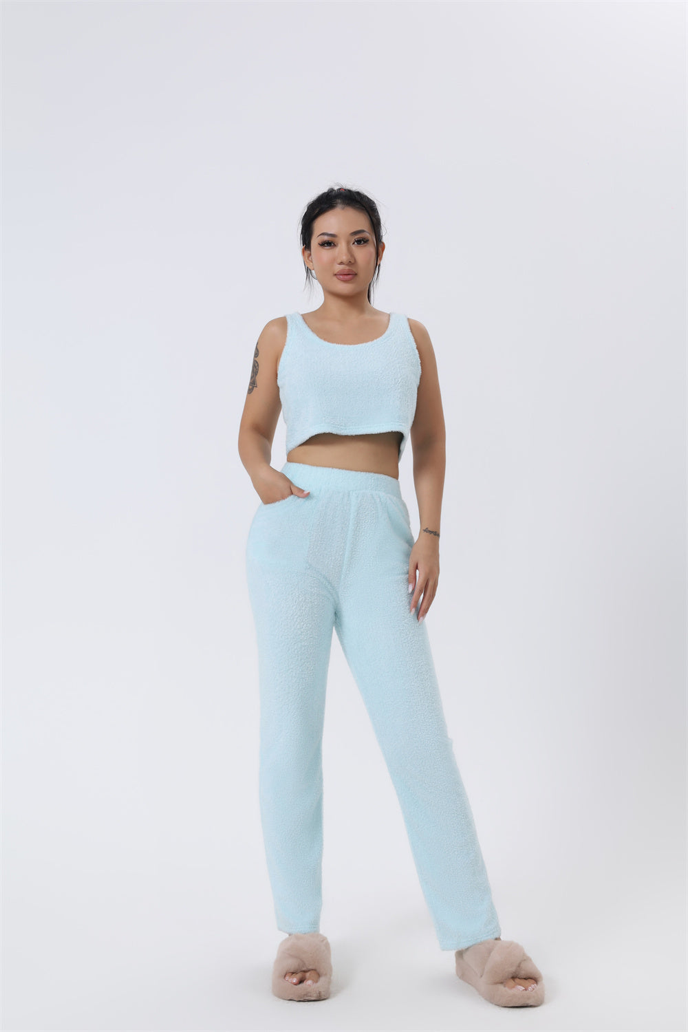 Woman wearing a light blue crop top and pants on a white background
