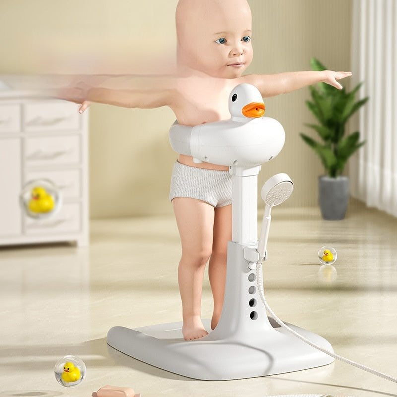Baby standing on a white stand with duck design, surrounded by rubber ducks and a plant in the background.