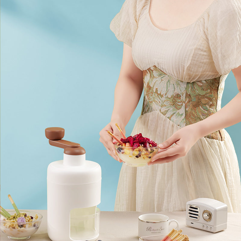 A person holding a bowl of cereal topped with fruits next to a white hand block shaving machine and a small white ice maker.