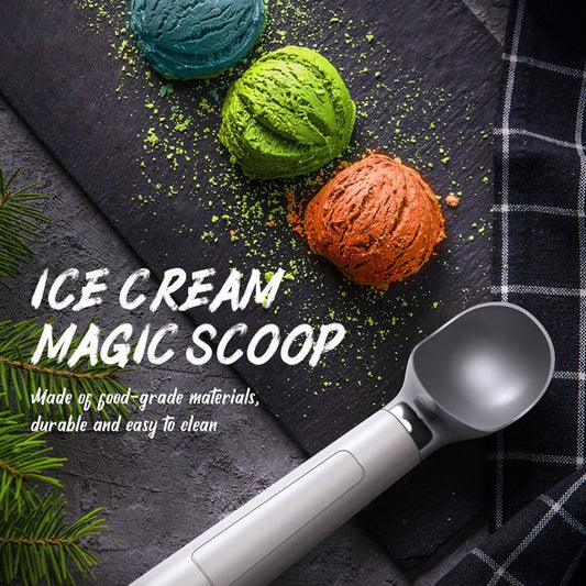 An ice cream scoop with a white handle and silver-colored stainless steel scooping surface, displayed alongside scoops of ice cream in green and red, with a checkered napkin and decorative pine leaves in the background.