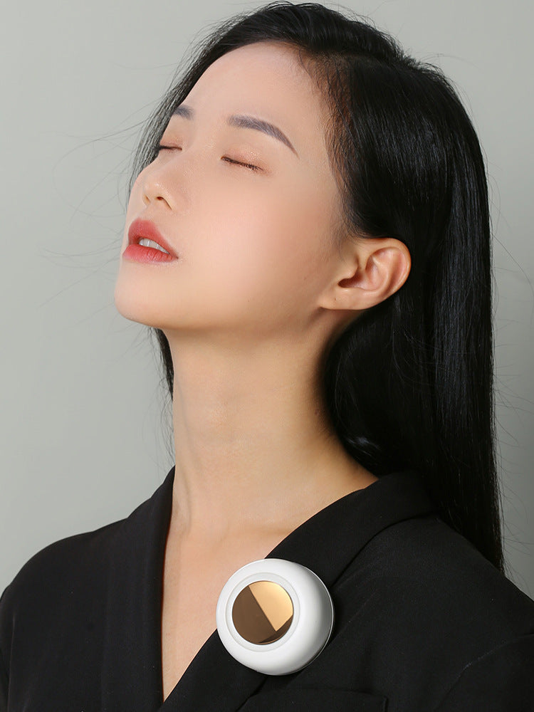 Woman wearing a white brooch with a gold center on a plain background