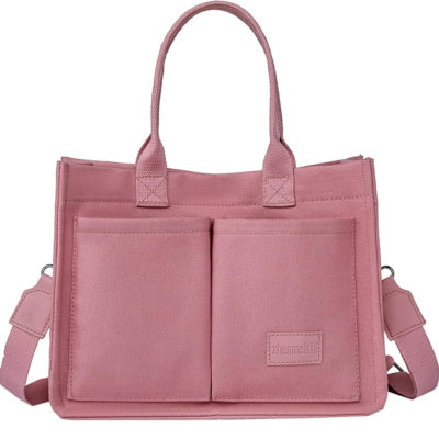 Pink handbag with multiple pockets and a shoulder strap on a white background