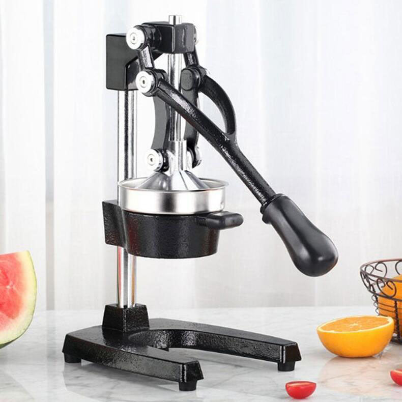 Manual juicer on a white countertop with fruits in the background