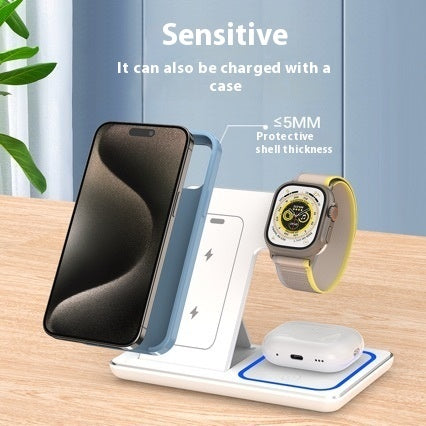 Wireless charging stand with phone, watch, and earbuds on a wooden surface.