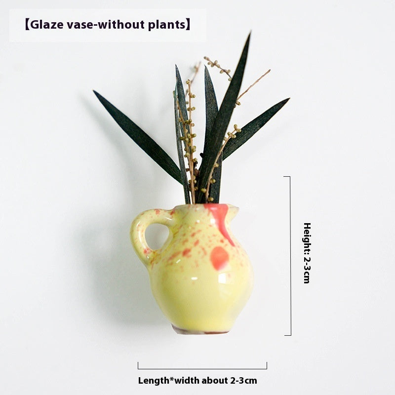 Yellow glaze vase with red accents holding plants on a white background