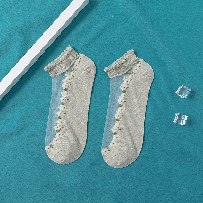 A pair of women's boat socks with a floral design in purple and white colors, worn with a pair of flat shoes.