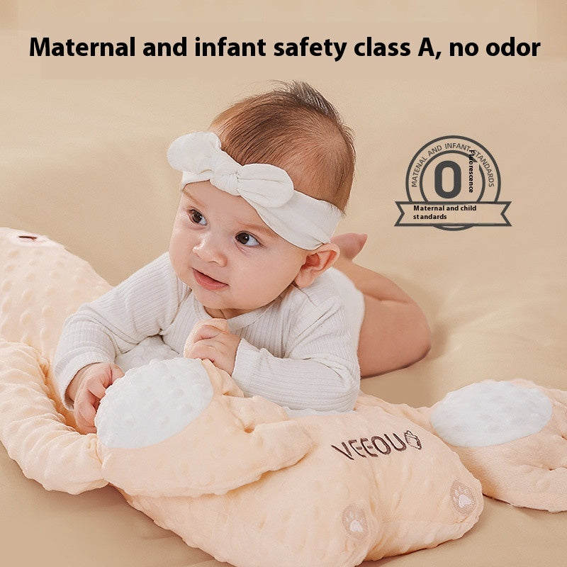 Baby lying on a soft, plush toy with 'VECOU' branding, against a beige background.
