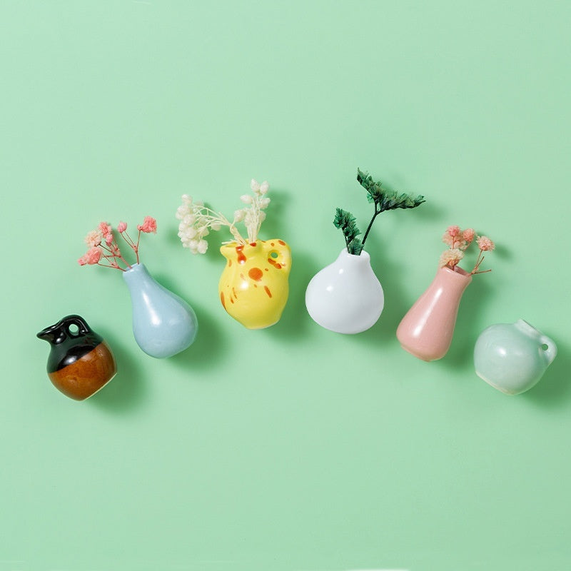 Set of colorful mini vases with plants on a light green background